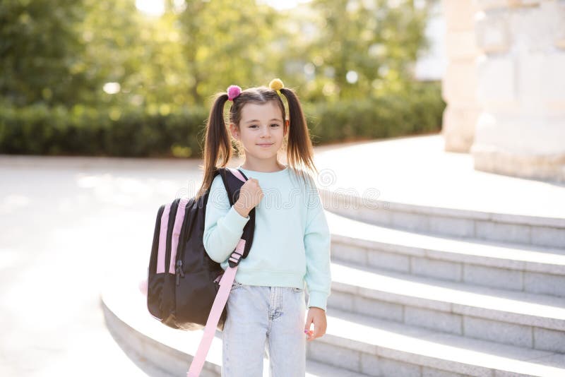 Smiling sweet happy little kid girl 5-6 year old wear casual clothes and backpack. Pupil child prepare for studying. Back to schoo