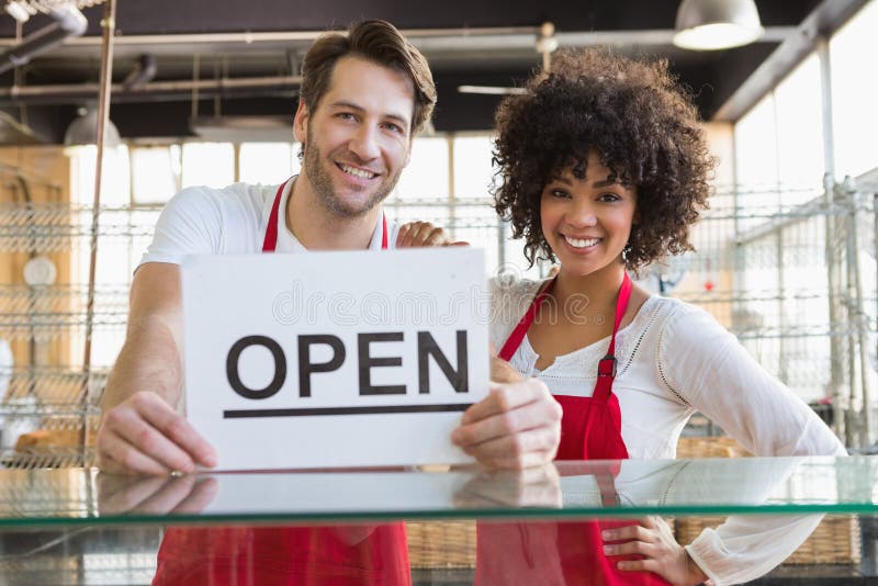 Smiling team posing behind the counter with open sign stock photos Smiling team posing behind the counter with open sign stock photos