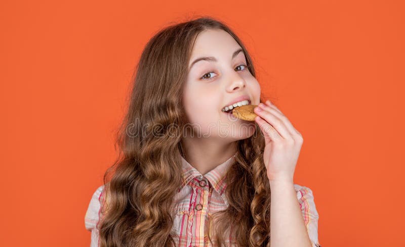 smiling teen girl eat oatmeal cookies on orange background