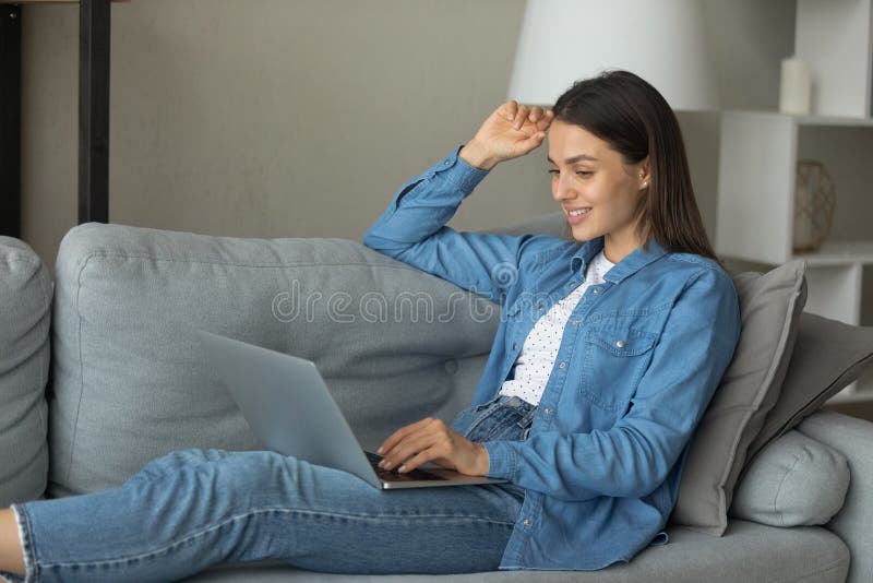 Smiling teenage female rest on sofa with laptop on knees