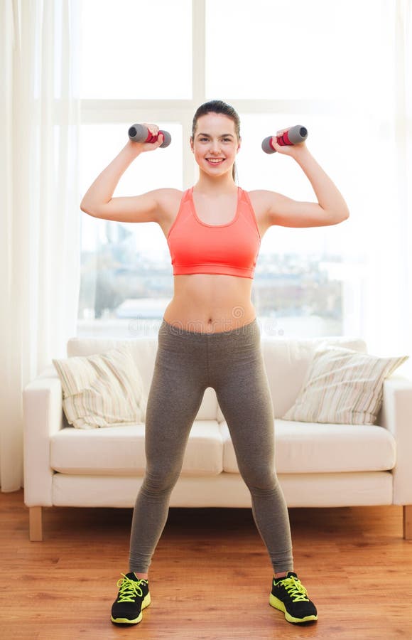 Smiling teenage girl exercising with dumbbells