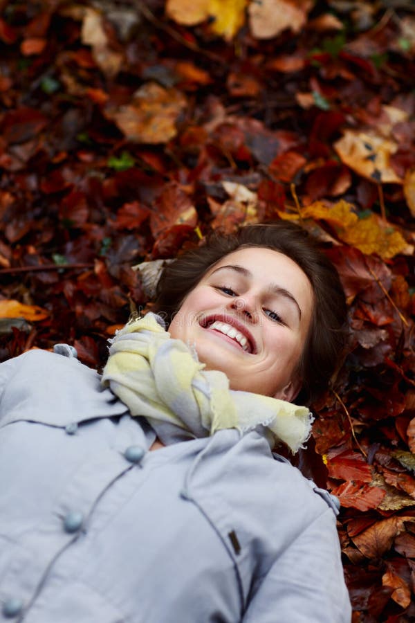 Smiling teenage girl lying in autumn leaves