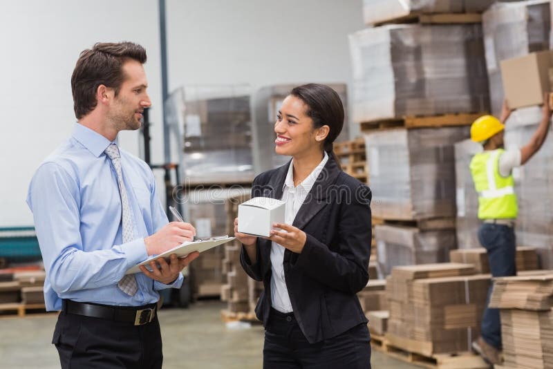 Smiling warehouse managers holding box and clipboard stock image