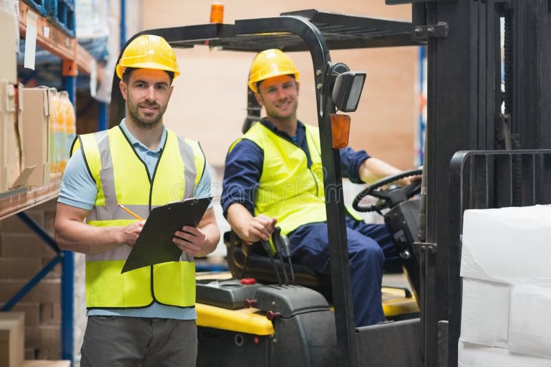Smiling warehouse worker and forklift driver stock images