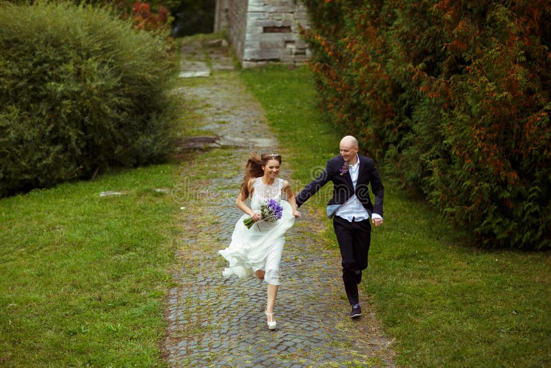 Smiling wedding couple run along the park stock images Smiling wedding couple run along the park stock images