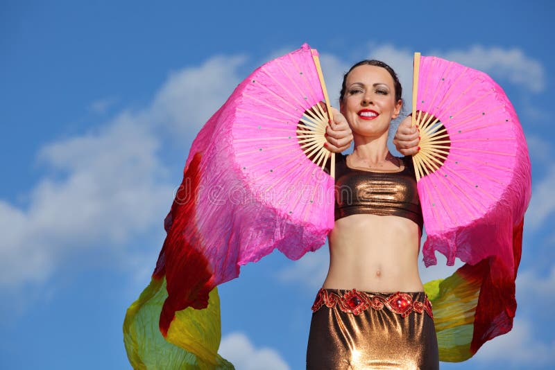 Smiling woman dances with pink veil fans