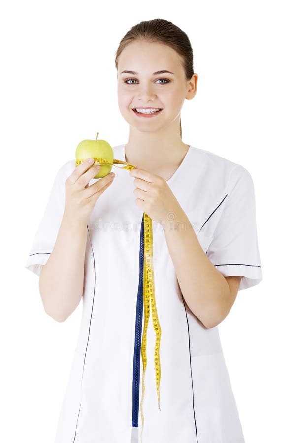 Smiling woman doctor with a green apple and measuring tape.