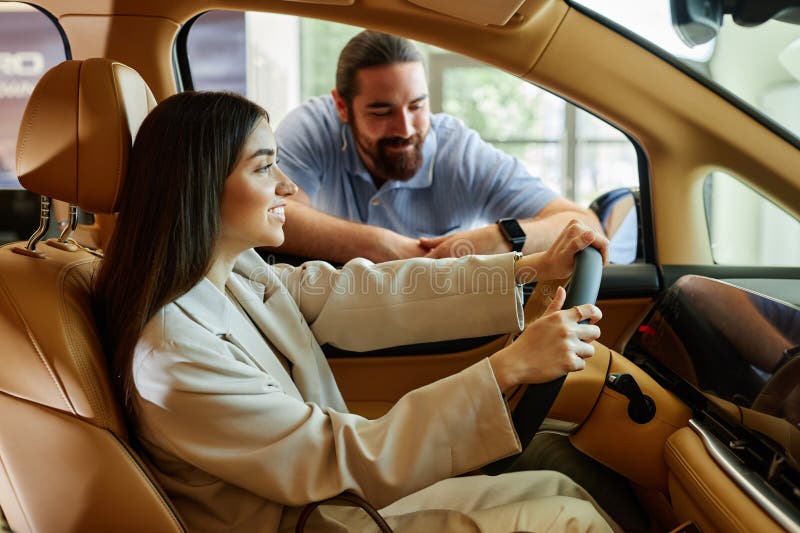 Smiling Woman at Drivers Seat Testing New Car with Boyfriend at Dealership Center royalty free stock photo