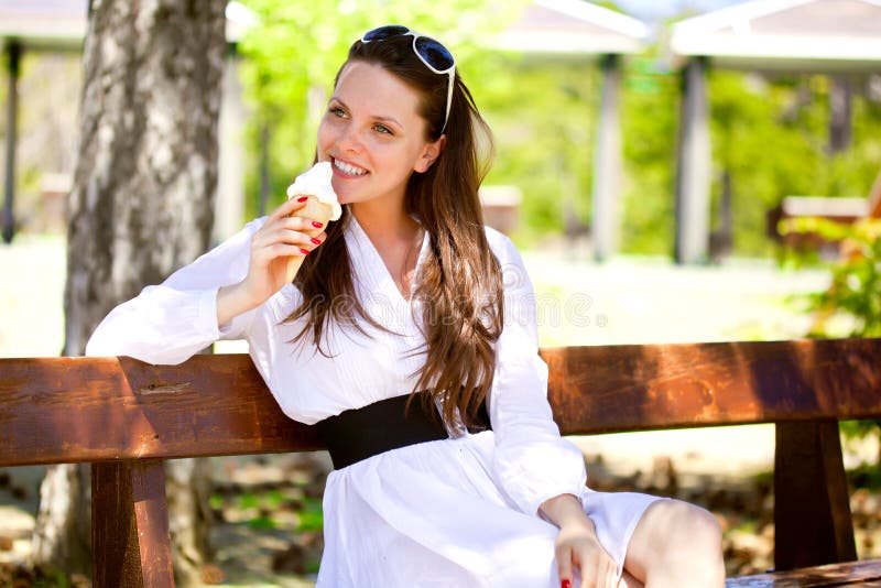 A smiling woman is eating an ice cream