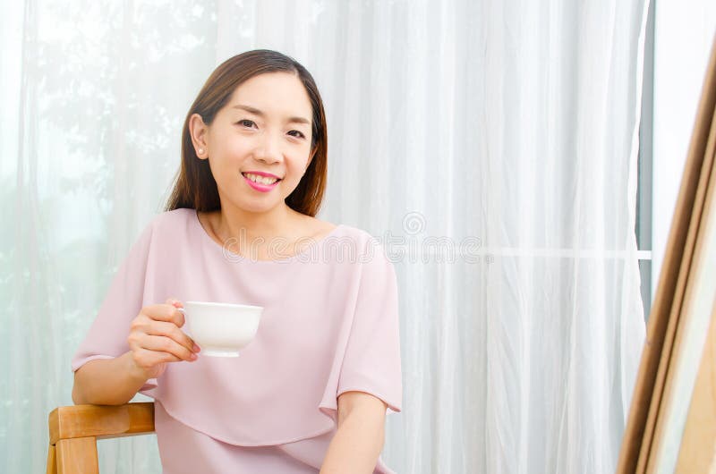 Smiling woman female artist painting picture on canvas with oil paints at my home as her hobby, Looking picture drinking coffee stock images Smiling woman female artist painting picture on canvas with oil paints at my home as her hobby, Looking picture drinking coffee stock images
