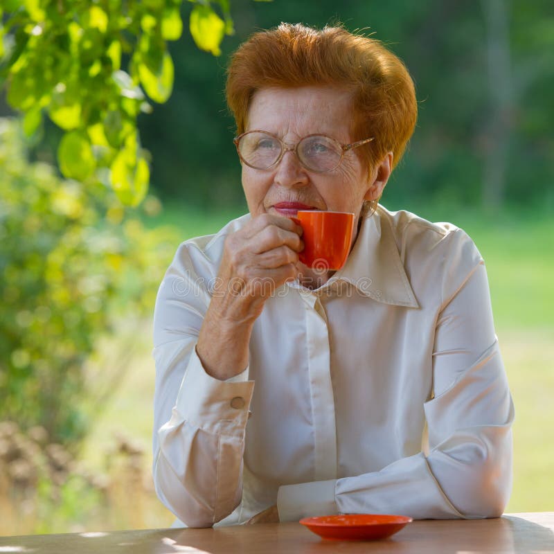 Smiling woman in glasses is drinking coffee outdoors. stock photography Smiling woman in glasses is drinking coffee outdoors. stock photography