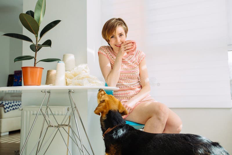 Smiling woman having break with coffee cup in cozy workplace at home interior. Happy female looking at camera and talking with her stock images Smiling woman having break with coffee cup in cozy workplace at home interior. Happy female looking at camera and talking with her stock images
