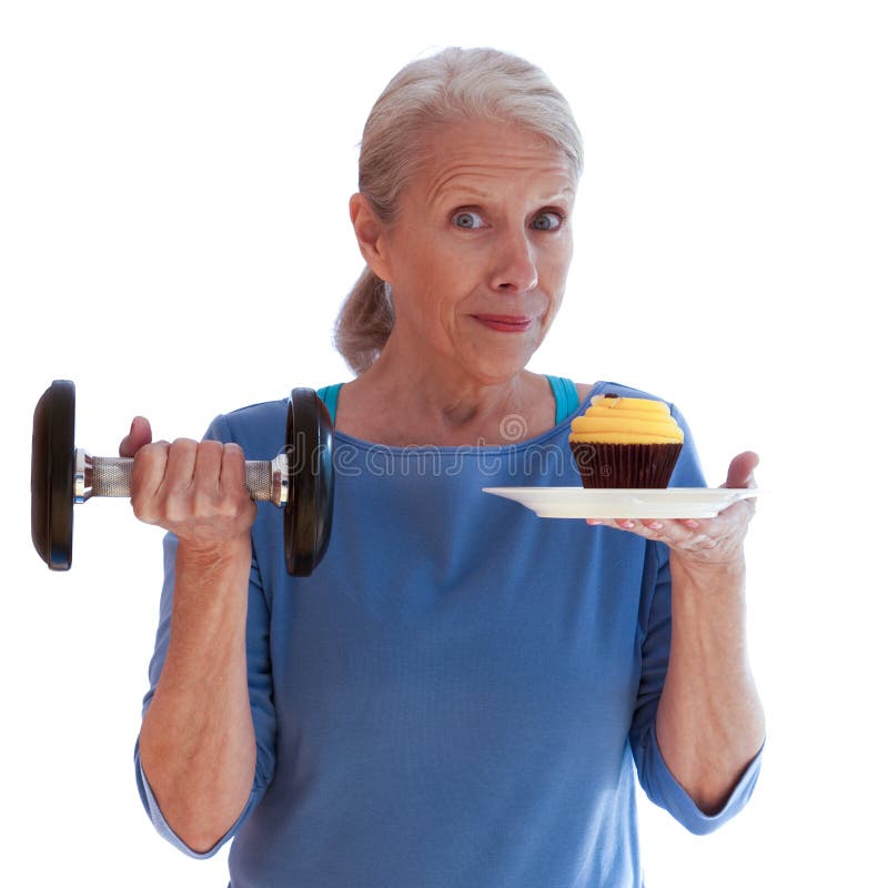 Smiling Woman Holding Dumbbell and Cupcake. Attractive middle-aged woman smiles as she decides between exercise and a cupcake royalty free stock photo Smiling Woman Holding Dumbbell and Cupcake. Attractive middle-aged woman smiles as she decides between exercise and a cupcake royalty free stock photo