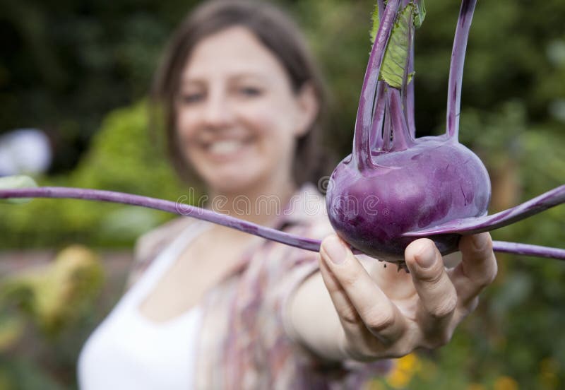 A smiling woman holding a Kohl Rabi