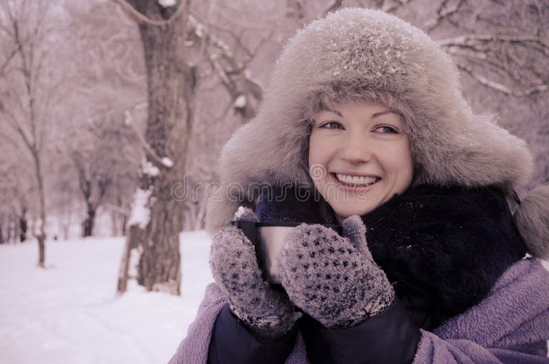 Smiling woman holding a travel mug in winter stock images Smiling woman holding a travel mug in winter stock images