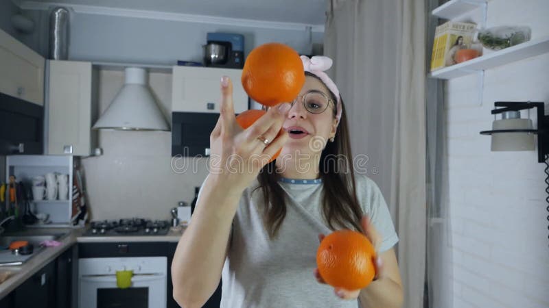 Smiling woman juggles fruits in the kitchen. Funny positive video