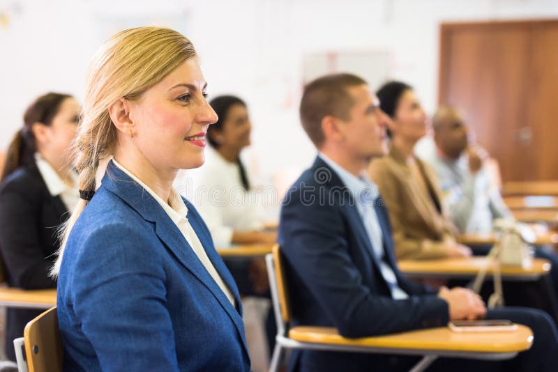 Smiling woman listening to speaker at business training stock photo