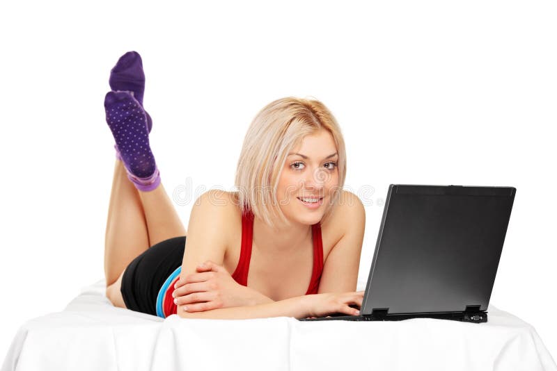 Smiling woman lying on a bed and laptop