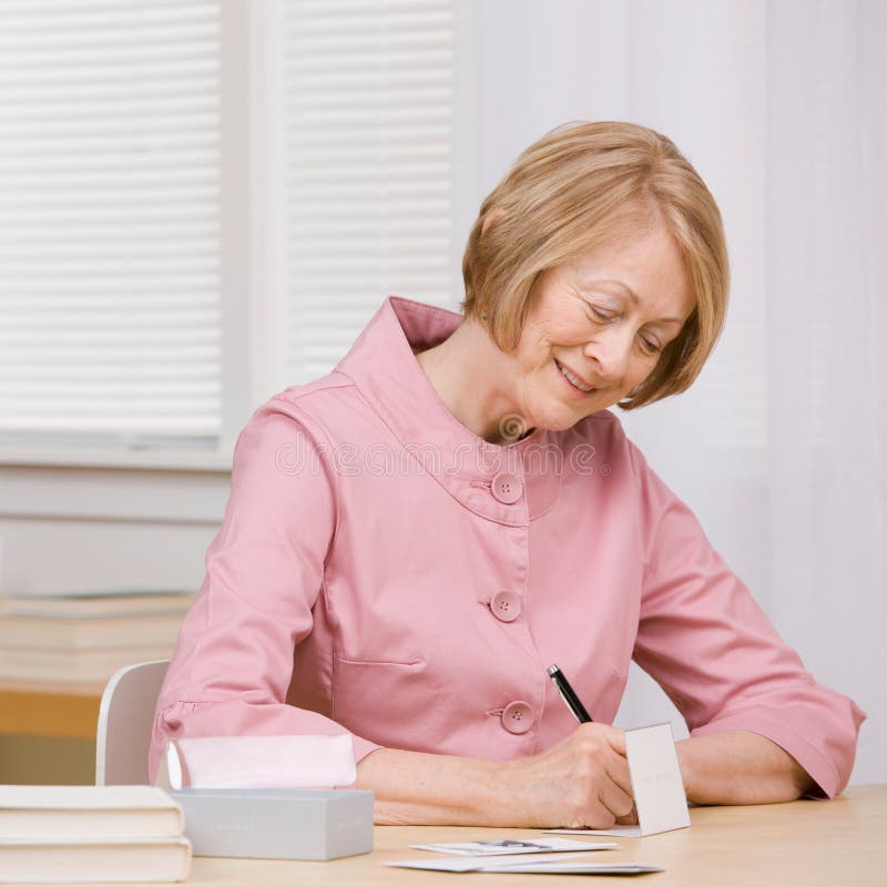 Smiling woman paying bills with checks at desk royalty free stock photo