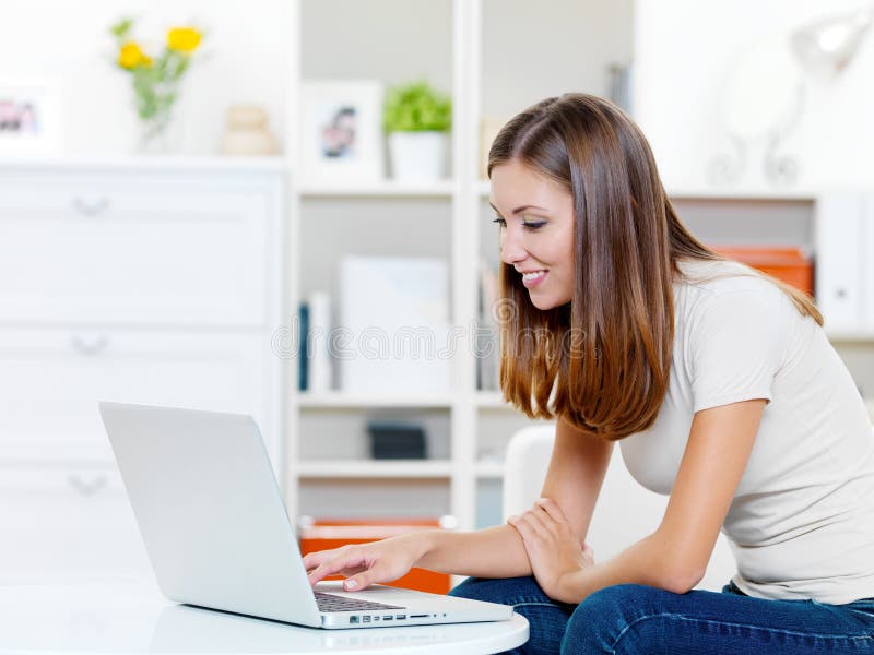 Smiling woman prints on the laptop stock photo