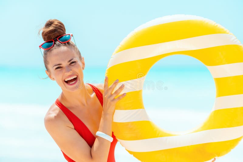 Smiling woman on seacoast showing yellow inflatable lifebuoy stock images Smiling woman on seacoast showing yellow inflatable lifebuoy stock images