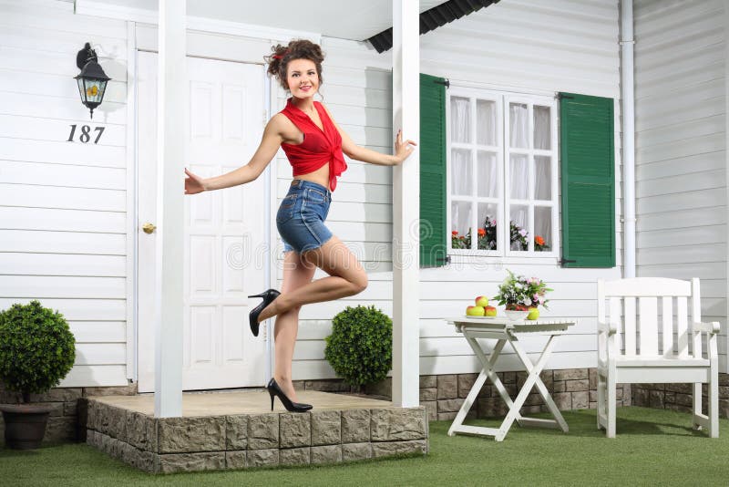 Smiling woman in shorts poses next to simple entrance door