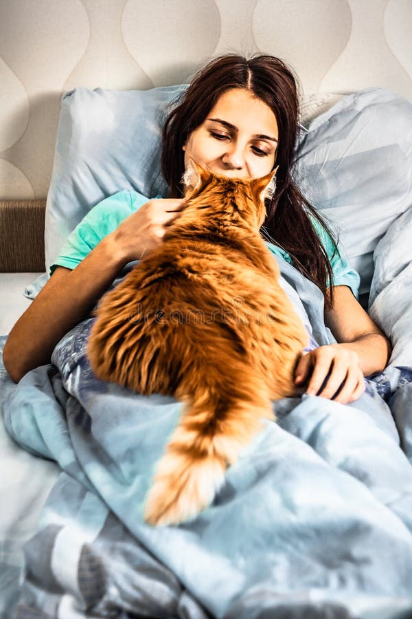Smiling Woman Waking Up after Sleep on Bed with Red Fatty Cat. Brunette ...