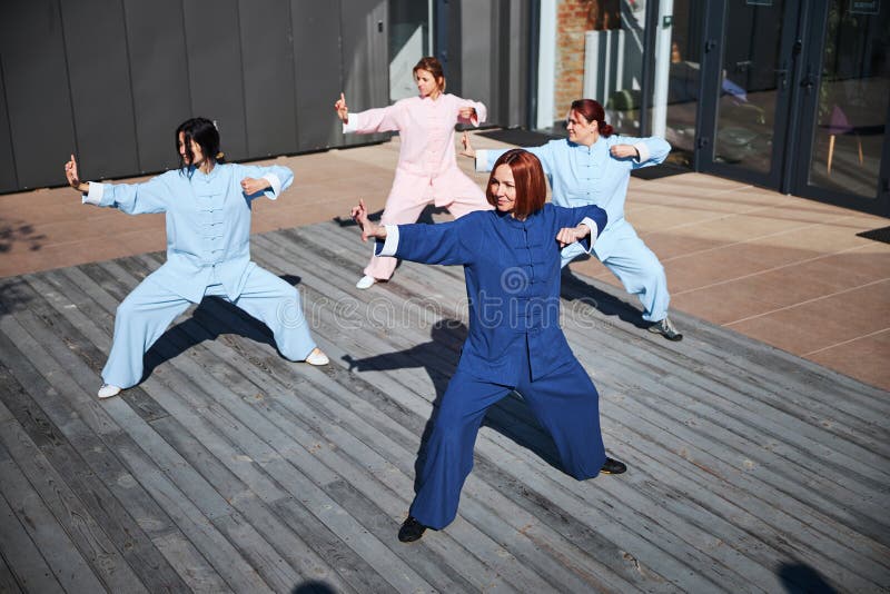 Confident young people practicing traditional Chinese martial arts outdoors and looking happy. Qigong class stock images, royalty-free photos and pictures