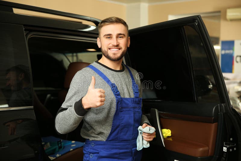 Smiling worker standing near car in shop. stock image Smiling worker standing near car in shop. stock image