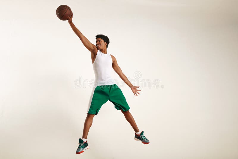 Smiling young black man reaching high for a basketball stock photo Smiling young black man reaching high for a basketball stock photo