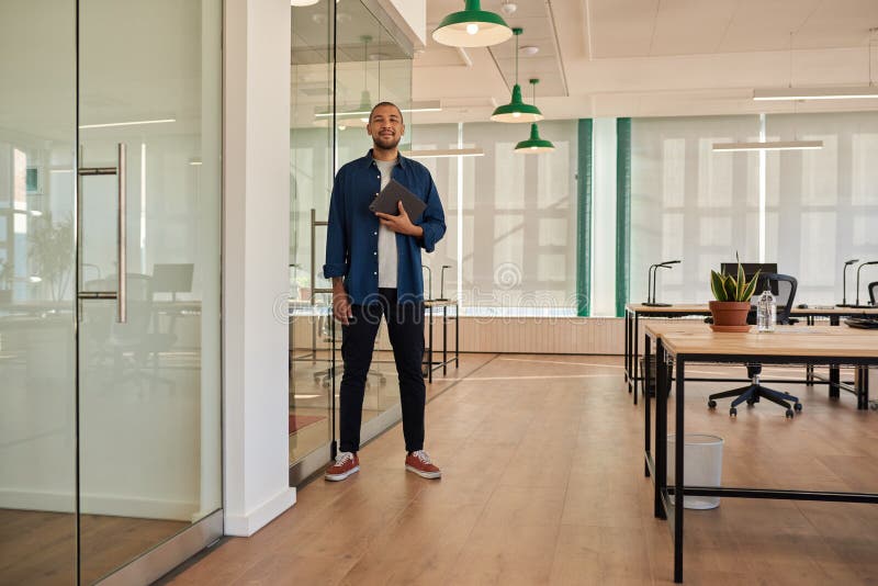 Smiling young businessman with a tablet standing in an office royalty free stock photography