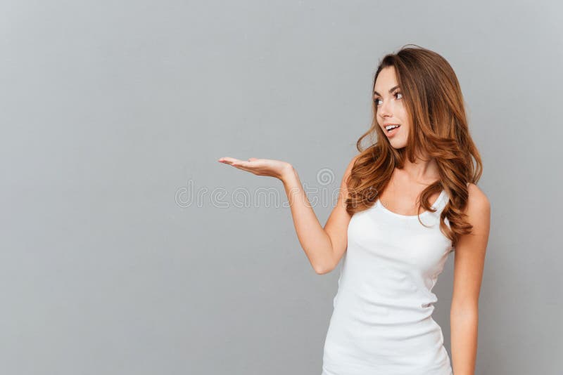 Smiling young businesswoman pointing pencil at blank clipboard