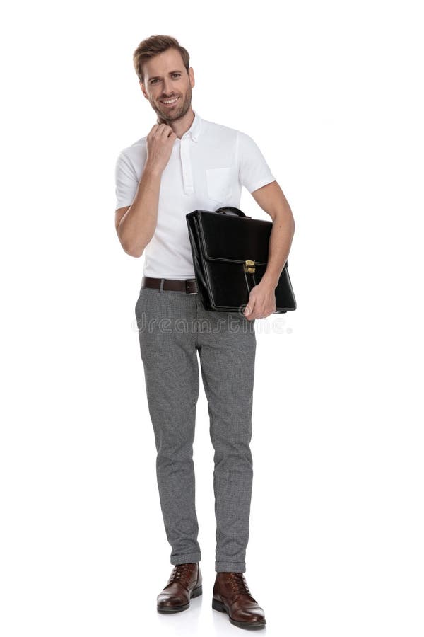 Smiling young casual man holding briefcase and adjusts his collar royalty free stock photography