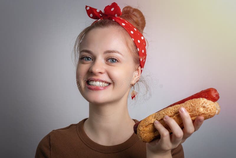 Smiling young Caucasian woman girl holding eating big size hot dog bun. Unhealthy fast food concept