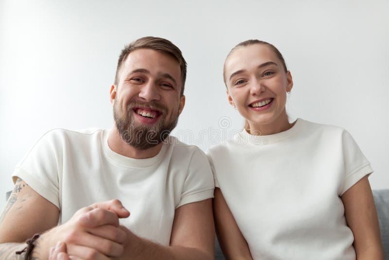 Smiling young couple looking at camera, making videocall, webcam