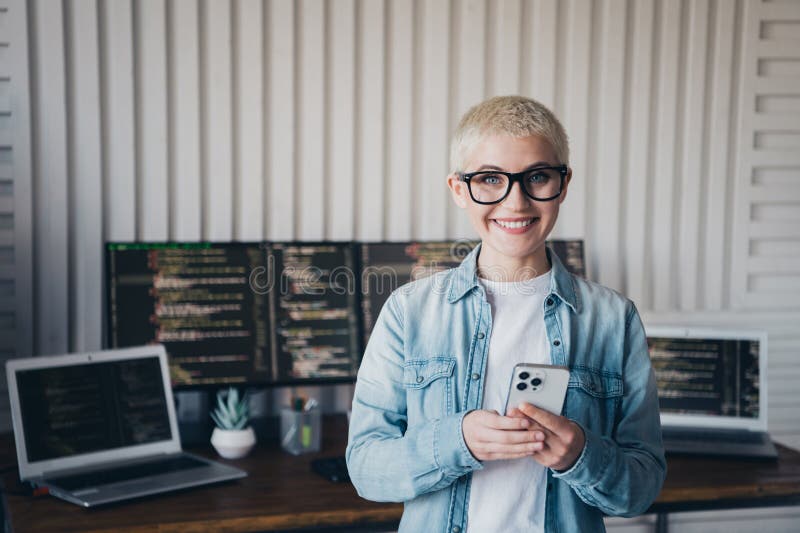 Smiling young female programmer using smartphone in home office with coding laptop and daylight stock photos