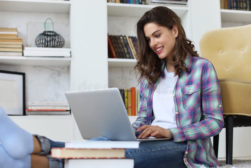 Smiling young female student studying at home and working with her laptop. Distance learning