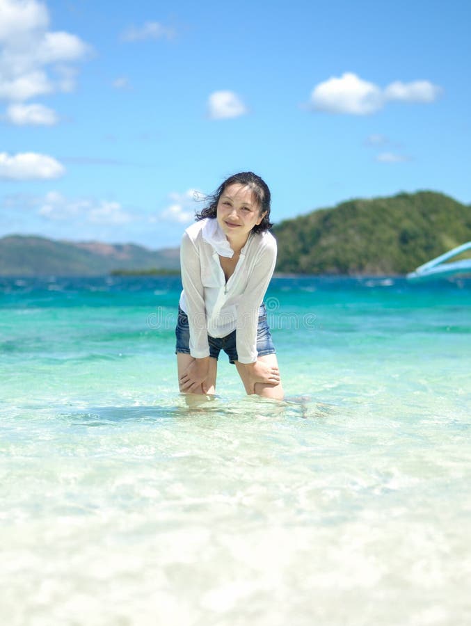 Smiling young girl stands in shallow water