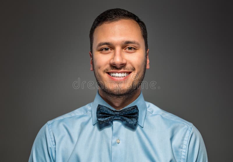 Smiling young man in blue shirt and butterfly tie