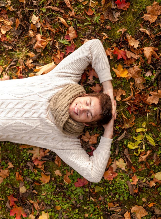 Smiling young man lying on ground in autumn park