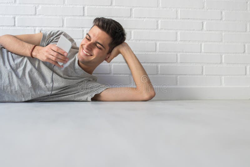 Smiling young man with mobile phone on the ground lying down young man with mobile phone on the ground lying down fotografia de stock