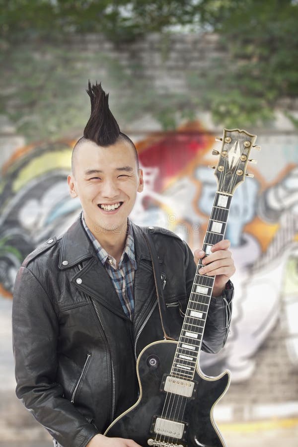 Smiling Young man with punk Mohawk holding guitar