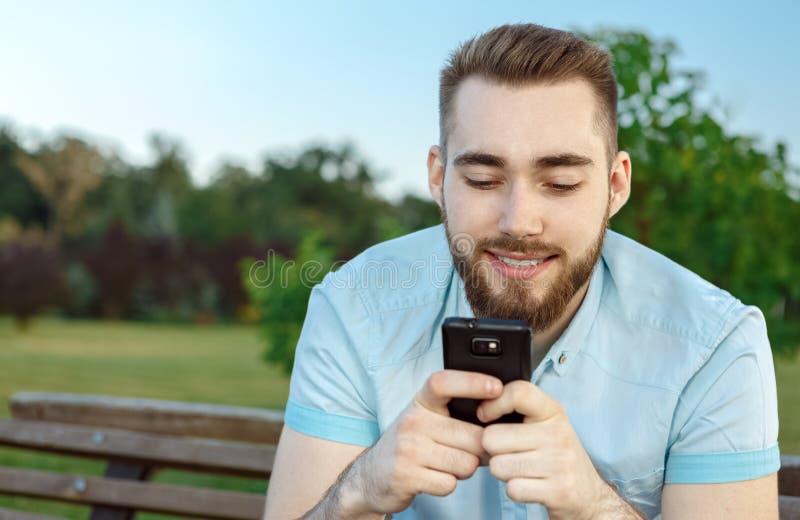 Smiling young man texting on the cellphone