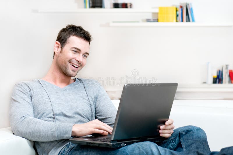 Smiling young man working on laptop stock photography