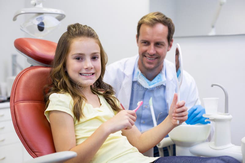 Smiling young patient holding mirror in in dental clinic