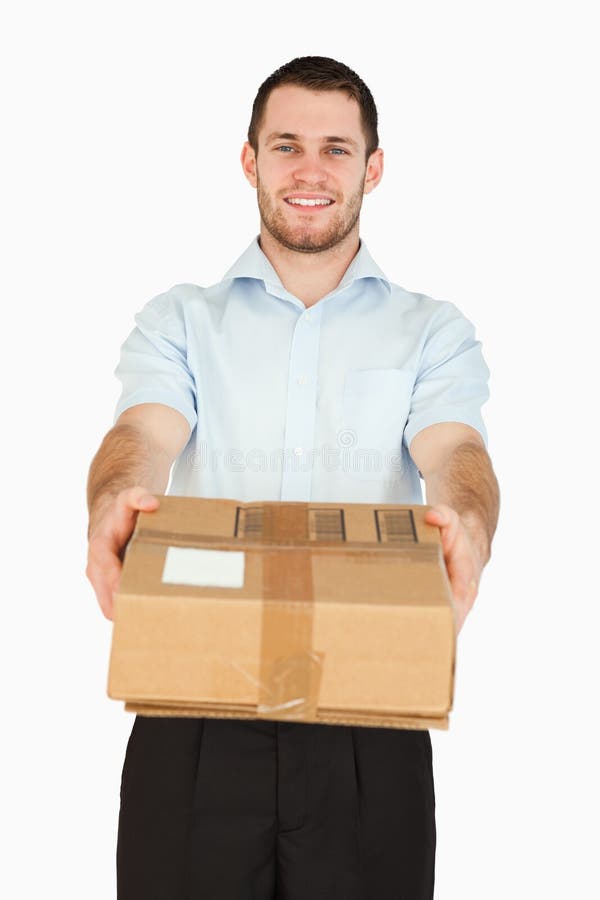 Smiling young post employee handing over parcel stock photography