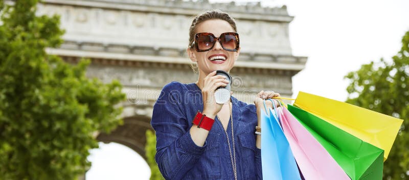 Smiling young trendy woman with shopping bags on Champ Elysees