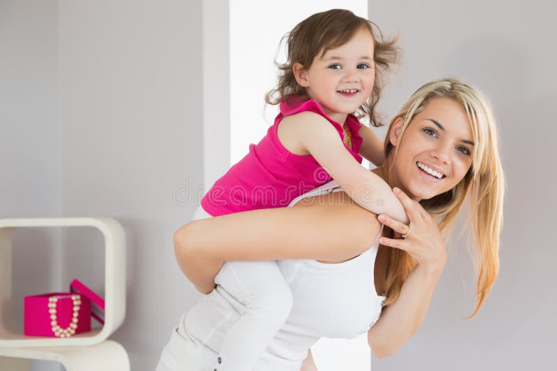 Smiling young woman carrying daughter stock photo Smiling young woman carrying daughter stock photo