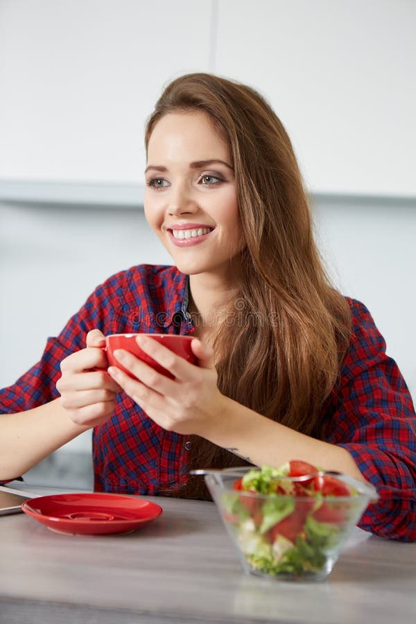 Smiling Young Woman Eating Fresh Salad in Modern Kitchen Stock Image