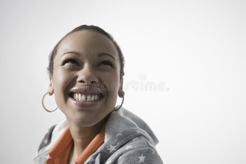 Smiling young woman looking up against gray background